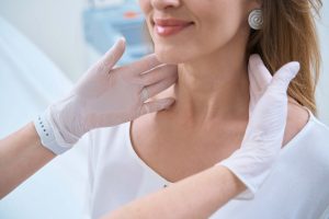 Dermatolog w rękawiczkach bada skórę szyi pacjenta z pięknym uśmiechem