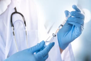 Lekarz pobiera za pomocą strzykawki preparat z ampułki